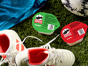 Two flavors of Pringles cups on green field with soccer cleats