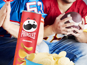 Pringles can with bowl of crisps with football fans in background 