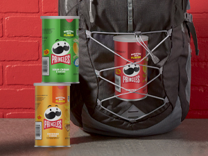 Book bag with grab and go can of Pringles crisps with red brick background
